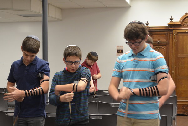 BOYS: Freshmen Zev Kent, Ezra Fax and Isaac Goor put on their tefillin at Shacharit.