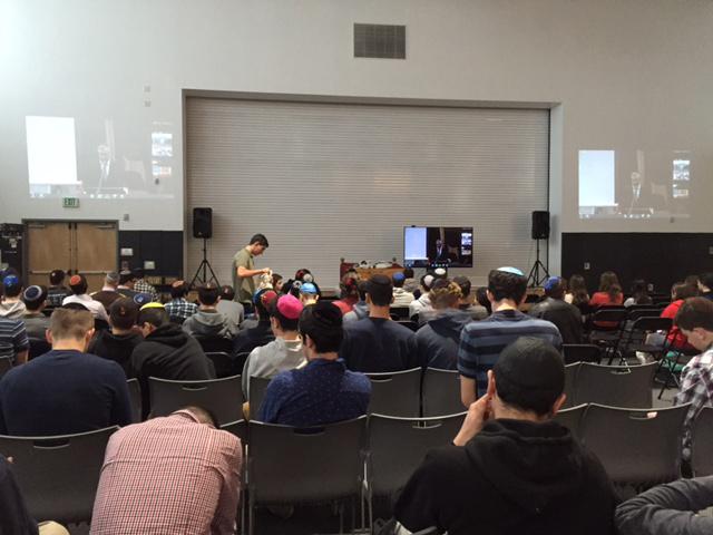 SOLIDARITY: Students  watch broadcast of Ezra Schwartzs shloshim in gym Dec. 21. Schools watching around the world could see one another. 