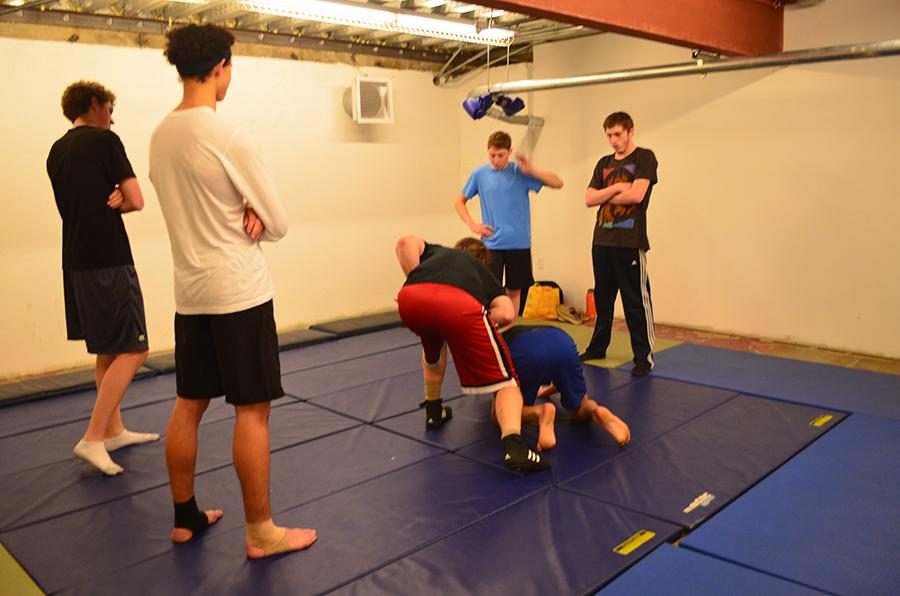 TAKE DOWN: Students watch as Mr. Reusch performs Russian 2-on-1, a jiu jiutsu move, on senior Daniel Soroudi. 