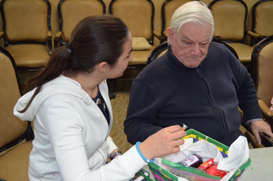 CHESED: Freshman Tara Chriki gave mishloach manot to a senior citizen at the Beverly Hills Carmel in March. She is among 10 female students who visit weekly to enhance the days of some of the residents. 