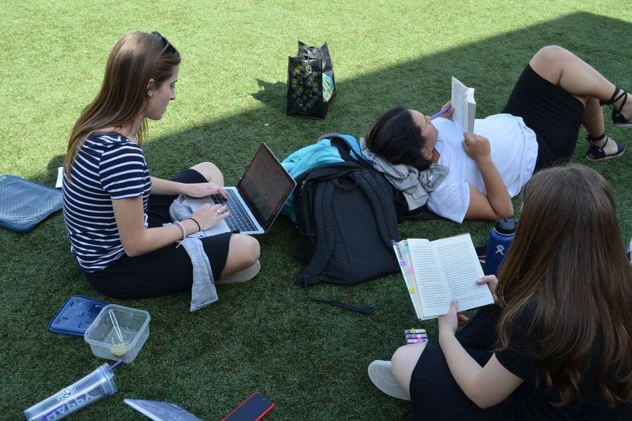 Concentration: Three seniors do their homework up on the turf. 