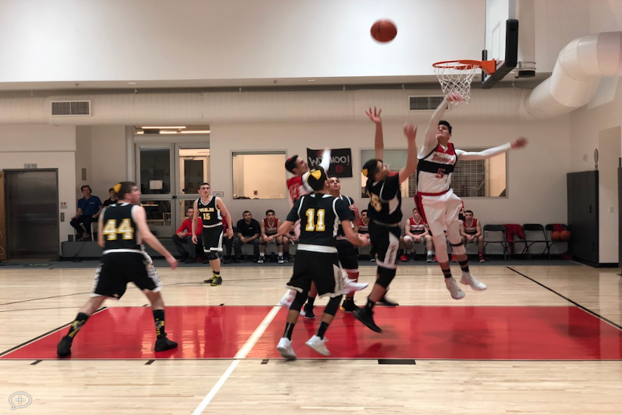 DOMINANT: Shalhevet center Ben Mashiach blocks a shot by YULA’s Joseph Sassoon Jan. 3. Ben said the pressure of the rivalry game worked to the Firehawks’ advantage.