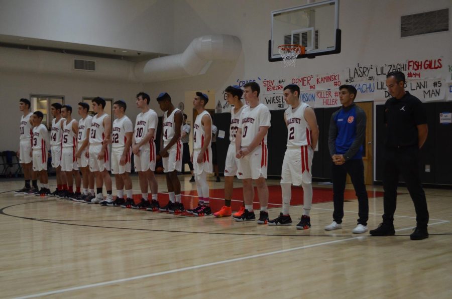 PAUSE:    Firehawk boys basketball team members paused on the court before the first game as Rabbi Block led 11 seconds of silence in honor of victims of the synagogue shooting in Pittsburgh.  Star guard Zack Muller, second from right in blue, did not play, but the Firehawks won anyway.