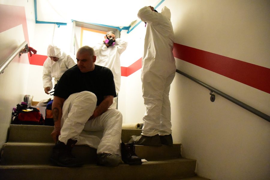 PROTECTION: Workers from 911 Restoration put on protective clothing before heading downstairs to the work area. According to Mr. Albert Garcia, those working in the area must wear protective clothing to avoid being exposed to any of the contaminants.