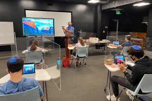 SAFETY: Dr. Josh Sharfman taught Computer Science in the Wildfire Theater during the first week of the summer classes. Desks were spaced six feet apart, and new plexiglass shields aimed to keep students’ air to themselves.