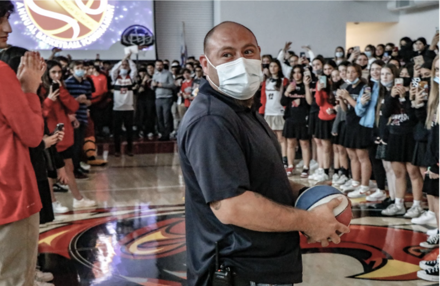 DUNK: Custodian Diego Cornejo getting ready to dunk the basketball as Shalhevet students and faculty surround the hoop yelling in excitement. 