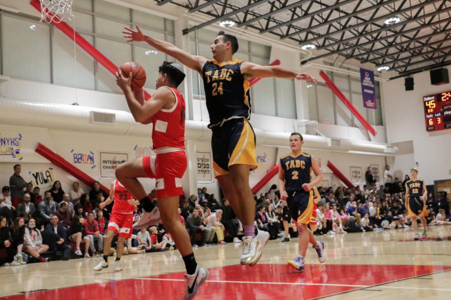 OVERPOWERED:  Gabriel Fogel, the lone sophomore on Shalhevet’s varsity team, is outmatched by TABC’s Netanel Benloulou as he drives to the hoop during the last minutes of the championship game Nov. 6.  The Firehawks lost, 75-51.
