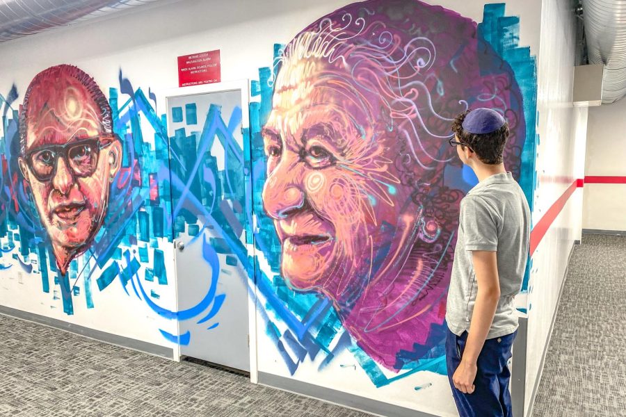SCALE: Freshman Etan Lerner takes a look at the massive murals of of early Israeli prime ministers Menachem Begin and Golda Meir in the basement hallway.