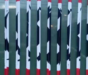 BORDER: Mr. ValaNejads Feb. 13 art installation was woven between angled panels of a LACMA security fence. Above, a section of the fence where the two different images — a swastika and an Islamic Republic of Iran flag — begin to morph into one another as a viewer passes by.