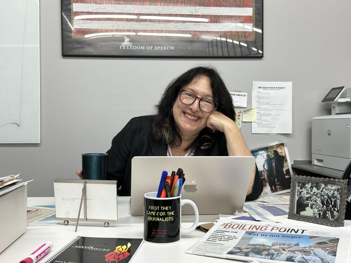 WORKING: Mrs. Keene perched at her desk in the Boiling Point office. She keeps a photo of her father with Reverend Dr. Martin Luther King Jr. (at left) for inspiration, as well as mugs with slogans and various newspapers. 
