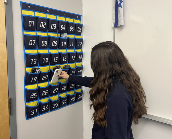 RULE: Freshman Romy Burg puts away her phone before class. Administration introduced the new policy requiring phones put away before all class periods and programs a few days before the start of the school year. 
