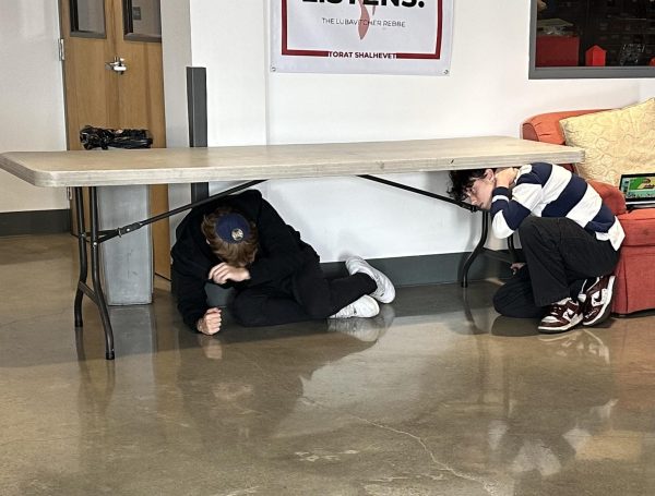 HIDING: Juniors Noah Selick and Sam Backer take cover under a table during the earthquake drill in October. The drill was part of a national earthquake awareness initiative called The Great ShakeOut. 